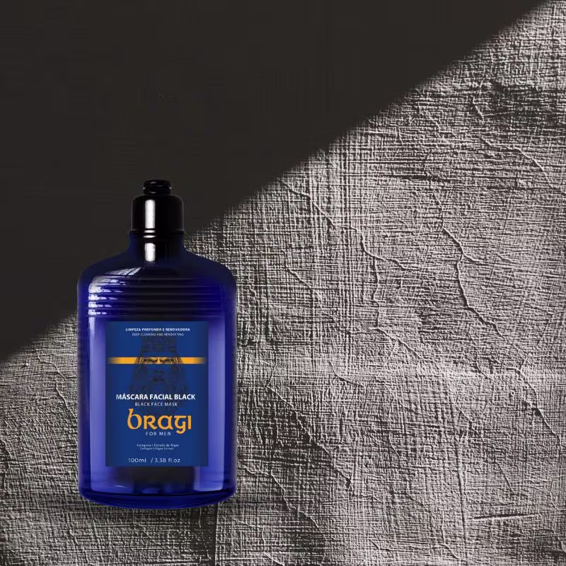 A imagem mostra uma garrafa azul grande da loção para barba, ao lado, há um fundo texturizado em tons de cinza, possivelmente um tecido ou material semelhante, criando um contraste interessante com o vidro azul brilhante do produto.