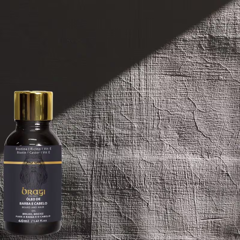 A imagem mostra um frasco preto com o óleo multifuncional, ao lado, há um fundo texturizado em tons de cinza, possivelmente um tecido ou material semelhante, criando um contraste interessante com o vidro preto brilhante do produto.