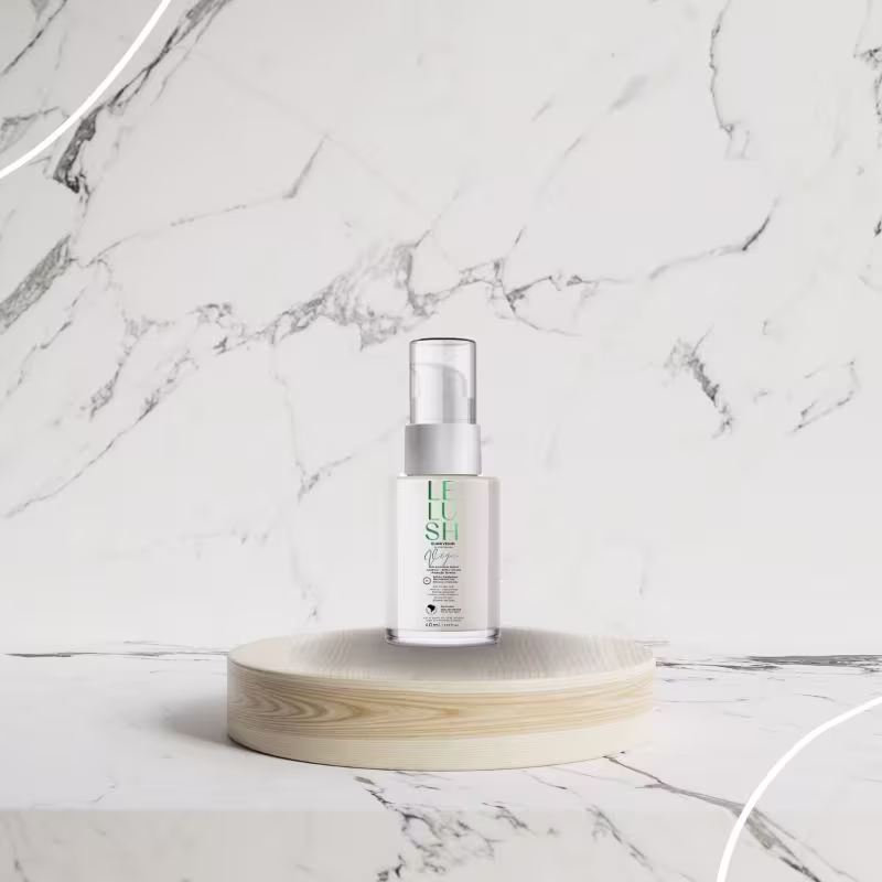 A imagem mostra o frasco do elixir capilar sobre uma base circular de madeira clara. O fundo é de mármore branco com veios cinza, dando um visual elegante e sofisticado ao produto exibido.