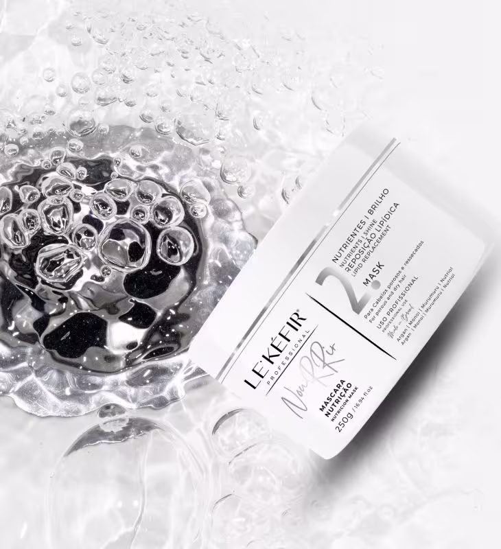 A imagem mostra a embalagem branca da máscara em destaque. Ao redor do frasco, há várias gotas de água formando uma textura borbulhante, sugerindo uma sensação refrescante e hidratante. A imagem transmite uma atmosfera bem clean.