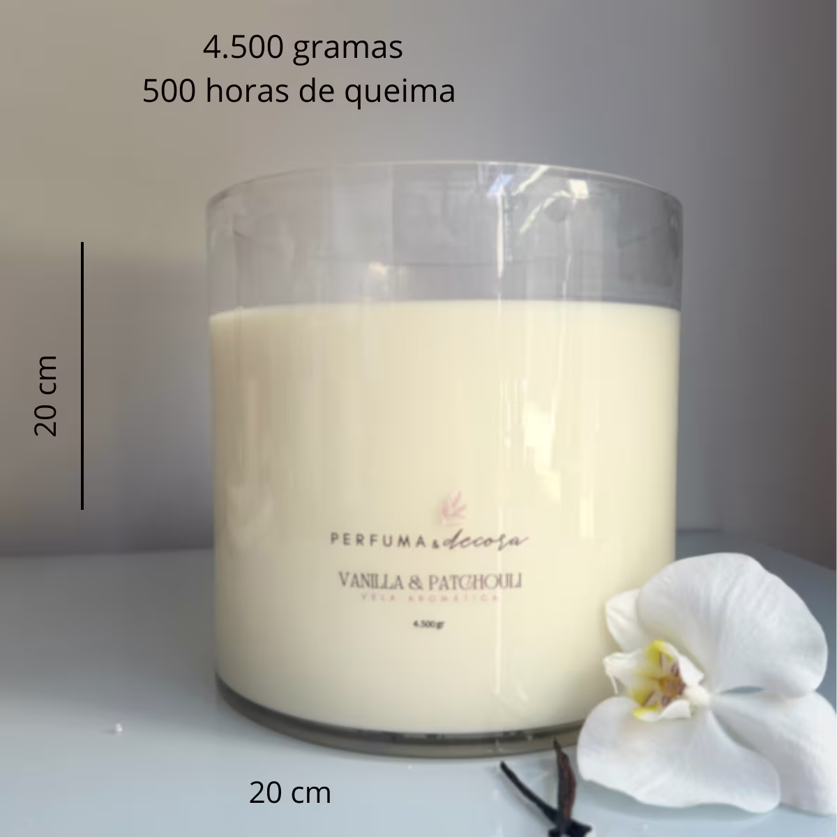 Vela perfumada grande de 4.500g na fragrância Vanilla & Patchouli. Embalagem cilíndrica de vidro transparente, contendo uma vela branca maciça. Ao lado, uma flor branca de orquídea. Dimensões fornecidas: 20 cm de altura.