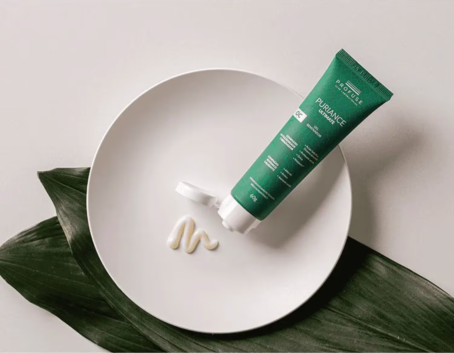 A imagem mostra o produto sendo colocado em um prato branco, embaixo existem suas folhas de árvores, verdes e grandes.