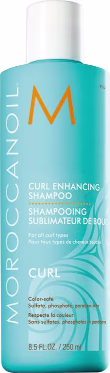 A imagem mostra o Shampoo Curl Enhancing 250ml da marca Moroccanoil. Embalagem na cor azul turquesa, com o logotipo "M" em laranja e o nome do produto em branco. Descrição adicional em texto indicando que é para todos os tipos de cacheados e ondulados.