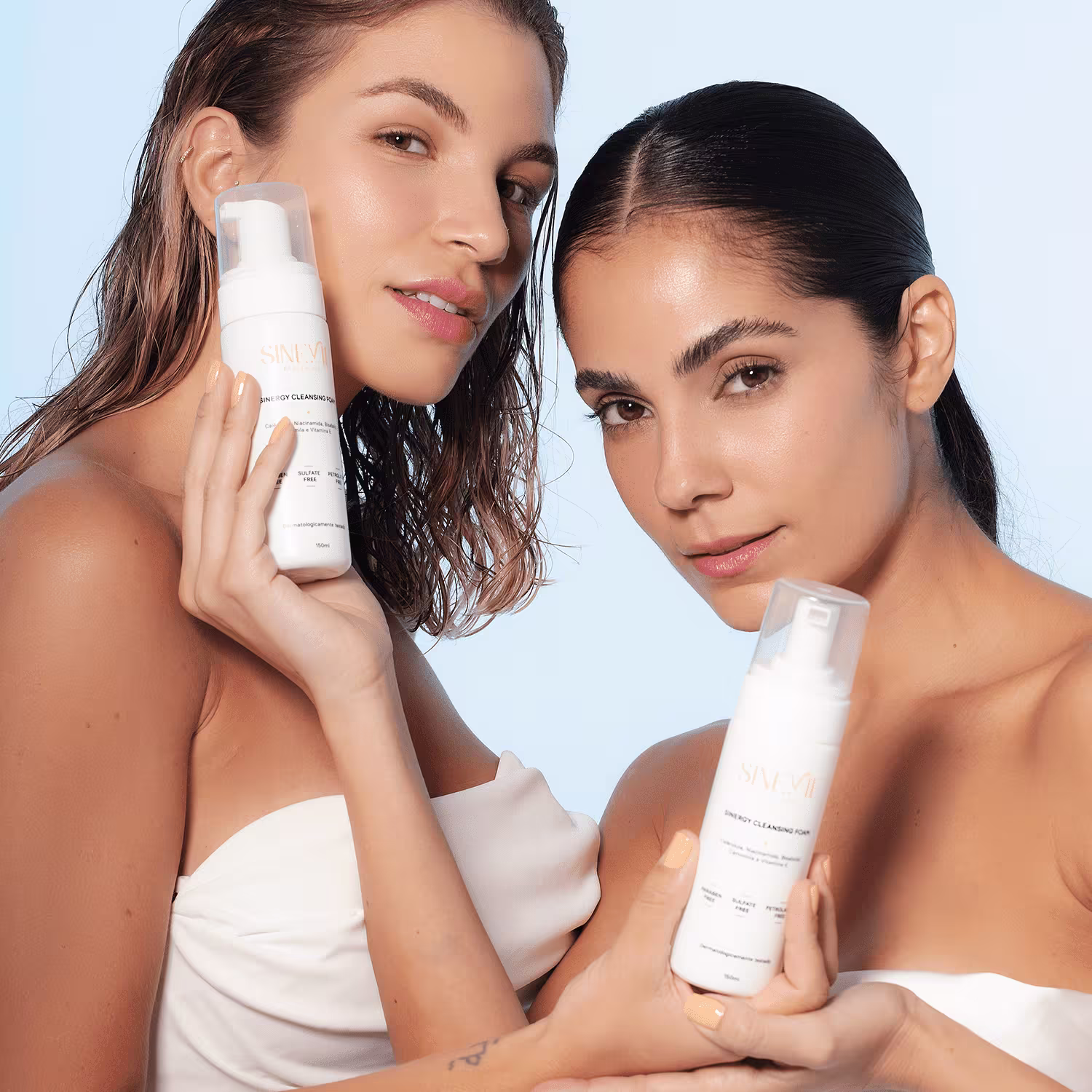 A imagem mostra duas modelos segurando um produto cada, próximo ao rosto.