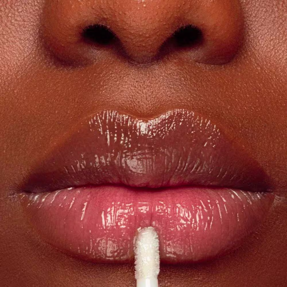 Gloss aplicado em lábios de pele negra.