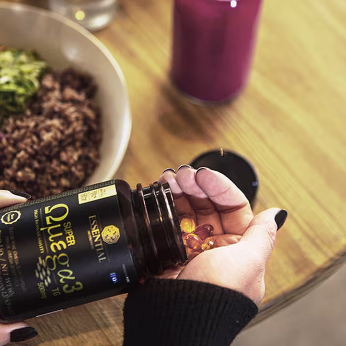 A imagem mostra uma mão pegando cápsulas da embalagem.