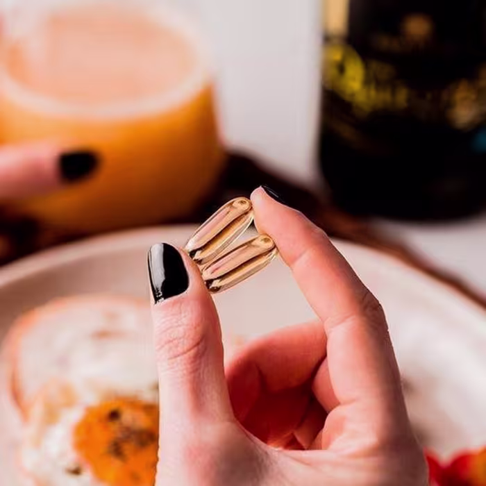 A imagem mostra uma mão segurando duas cápsulas.