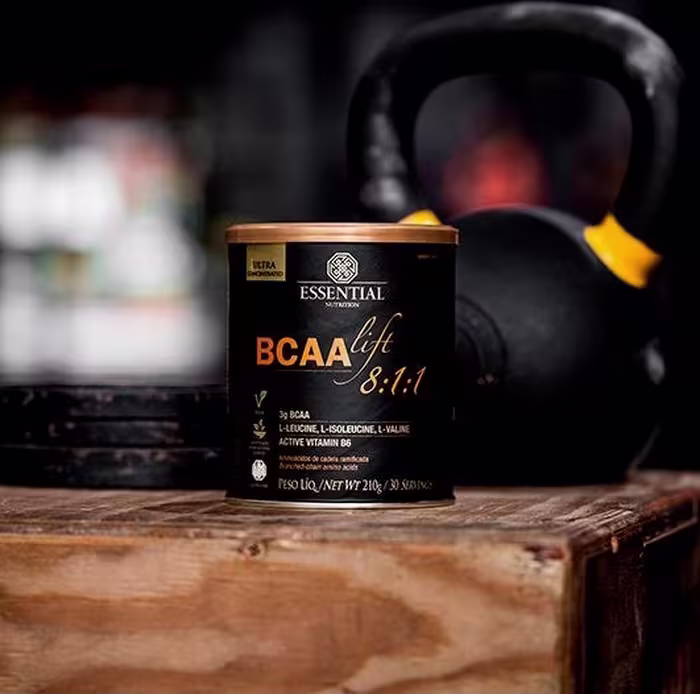 A imagem mostra uma lata preta, com letras douradas, próximo à um peso de academia.