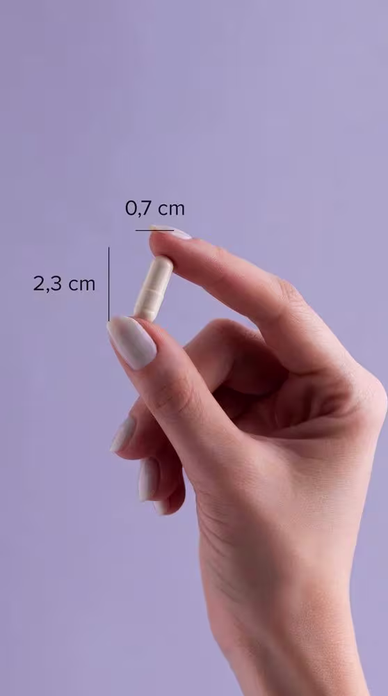 A imagem mostra uma mão segurando uma cápsula com o dedo polegar e o indicador, além de indicação de tamanho da cápsula: 0,7cm x 2,3cm.