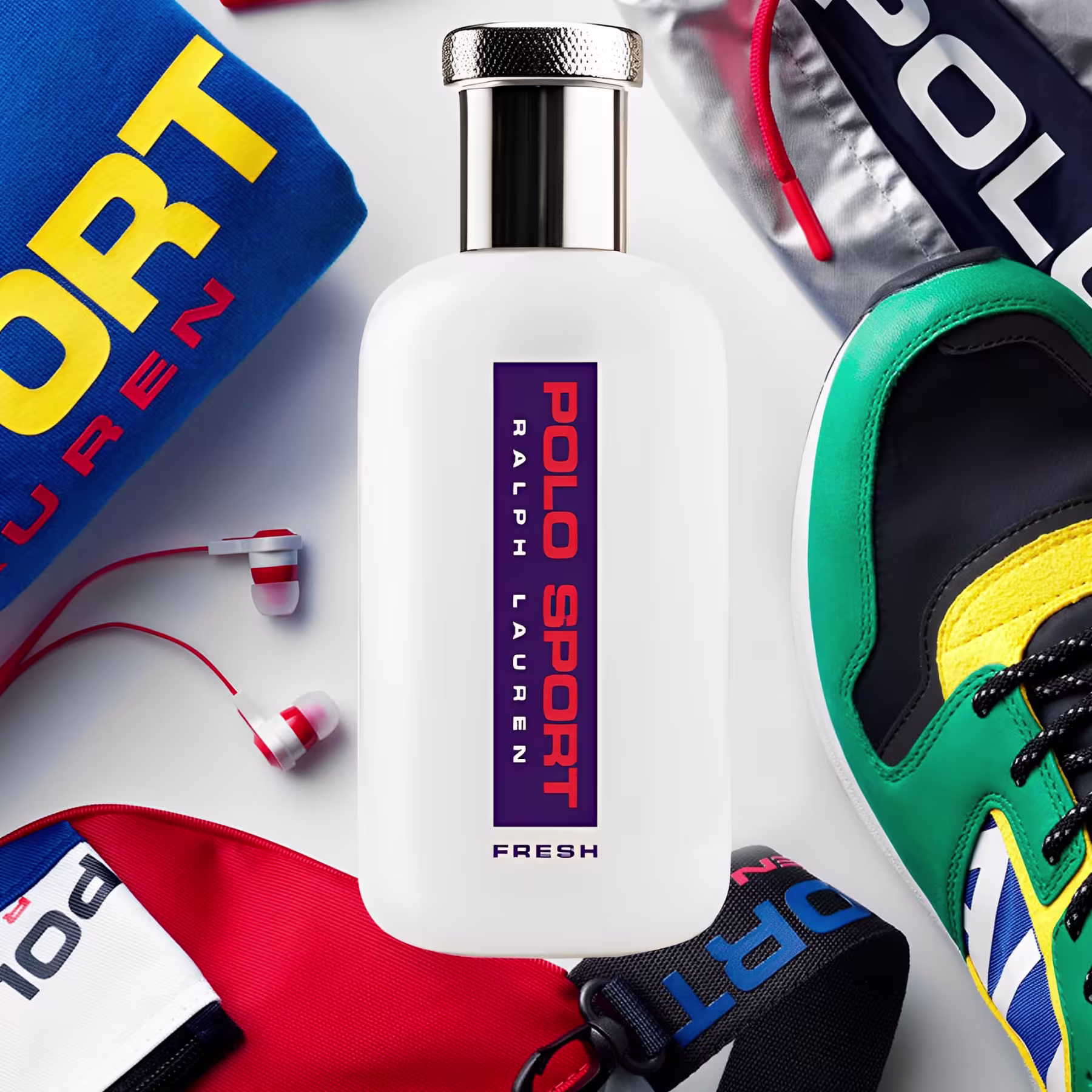 Perfume em frasco cilíndrico transparente com tampa metálica texturizada. A embalagem é branca com o logotipo "Polo Sport" em letras roxas e vermelhas, e a palavra "Fresh" em letras roxas na parte inferior.