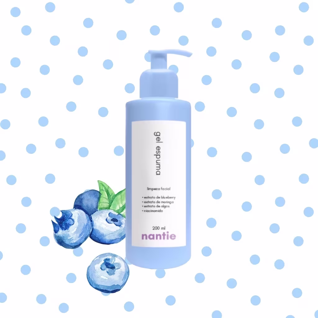 A imagem mostra o frasco do gel espuma de limpeza facial com ilustração de blueberries ao seu lado, com folhas verdes. Ao fundo tem um padrão de bolinhas na cor azul claro.