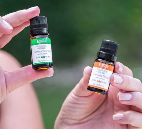 Dois frascos de óleos essenciais da marca Empório Essenza Serra Gaúcha, um com rótulo verde contendo Hortela Pimenta e outro com rótulo laranja contendo Laranja Doce, ambos em embalagens de vidro com tampas pretas.