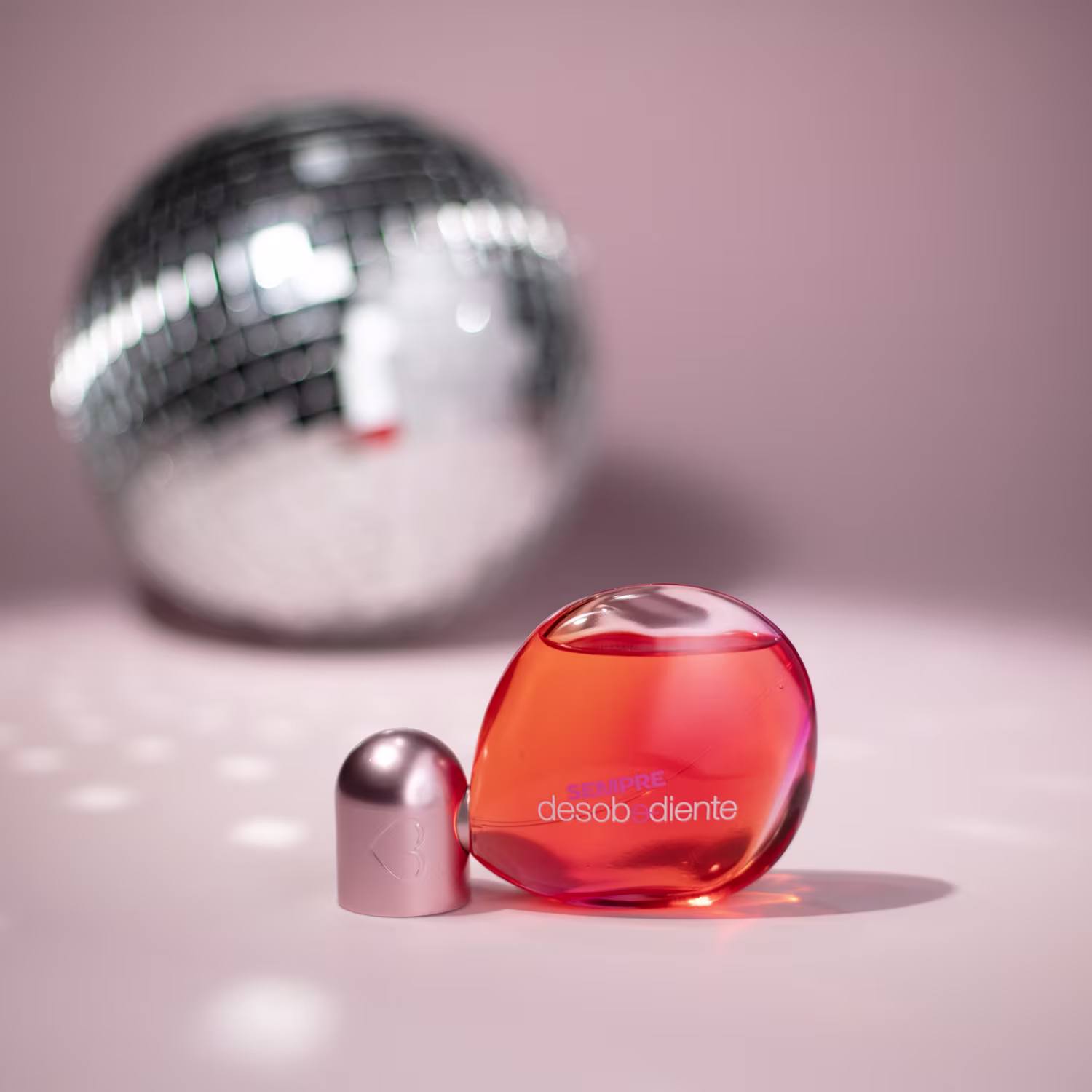 Imagem do perfume com um globo espelhado ao fundo.