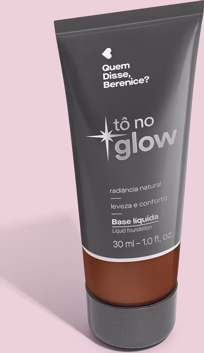 Base líquida em bisnaga preta com base transparente onde é possível ver o tom do produto. Fundo rosa.