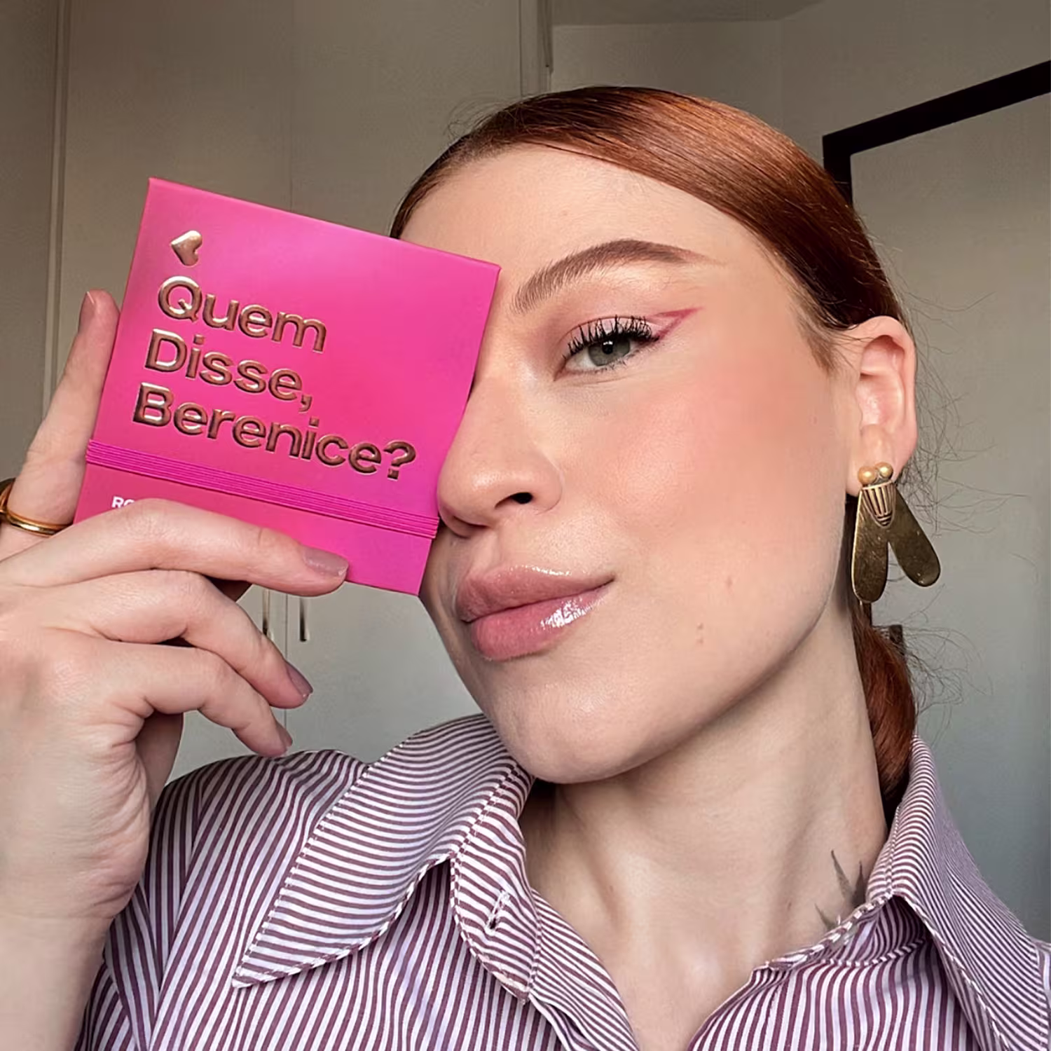 O texto na capa pergunta "Quem disse, Berenice?", indicando que se trata de um produto da marca de cosméticos e acessórios. A pessoa na imagem segura o item próximo ao rosto, com uma expressão pensativa.