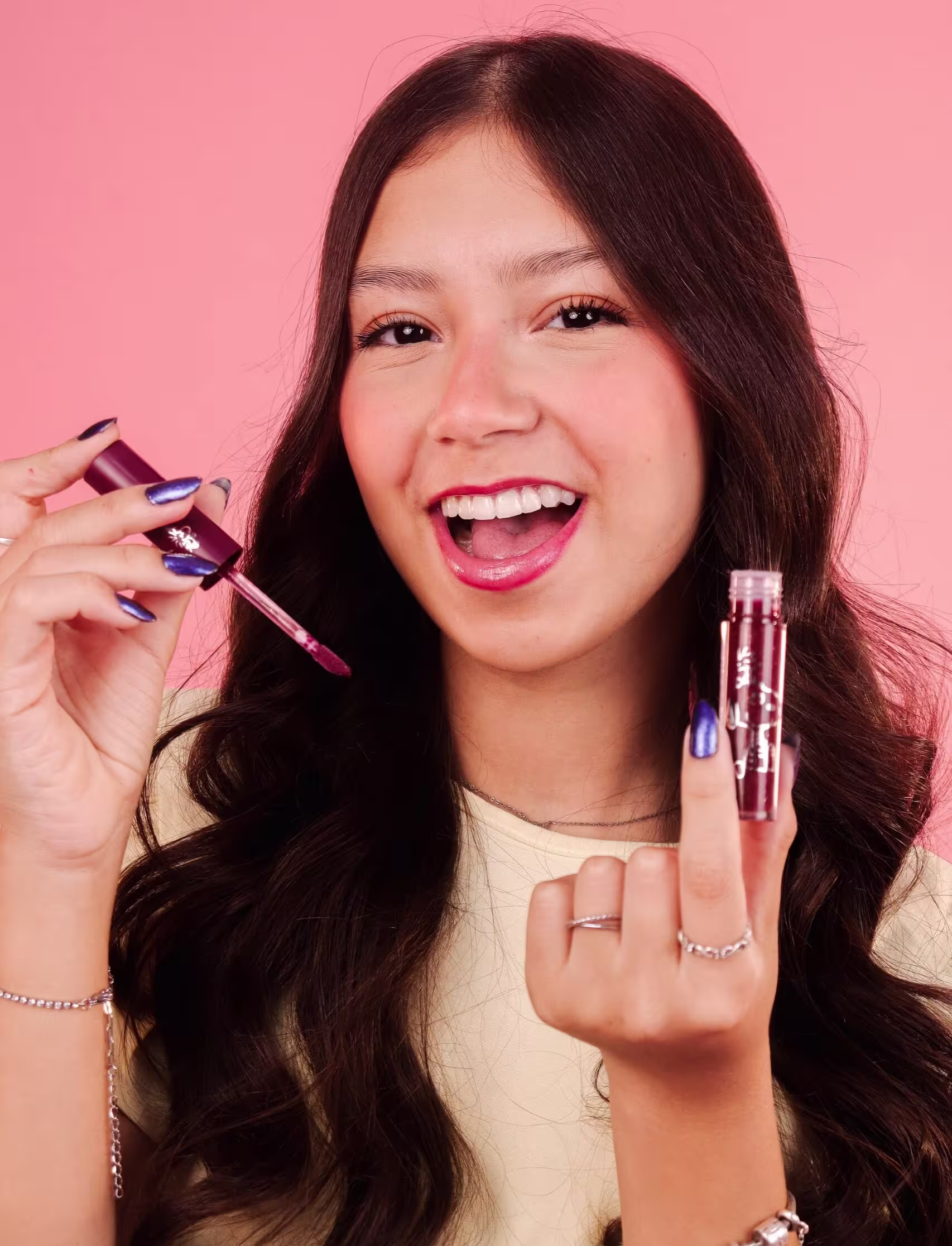 Modelo sorridente segura o gloss labial. Ela parece estar aplicando ou exibindo os produtos.