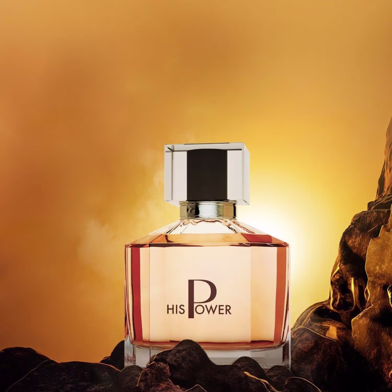 Perfume em frasco quadrado transparente com tampa cromada. O frasco está posicionado sobre pedras escuras em um cenário com um fundo alaranjado, sugerindo um pôr do sol ou ambiente desértico.