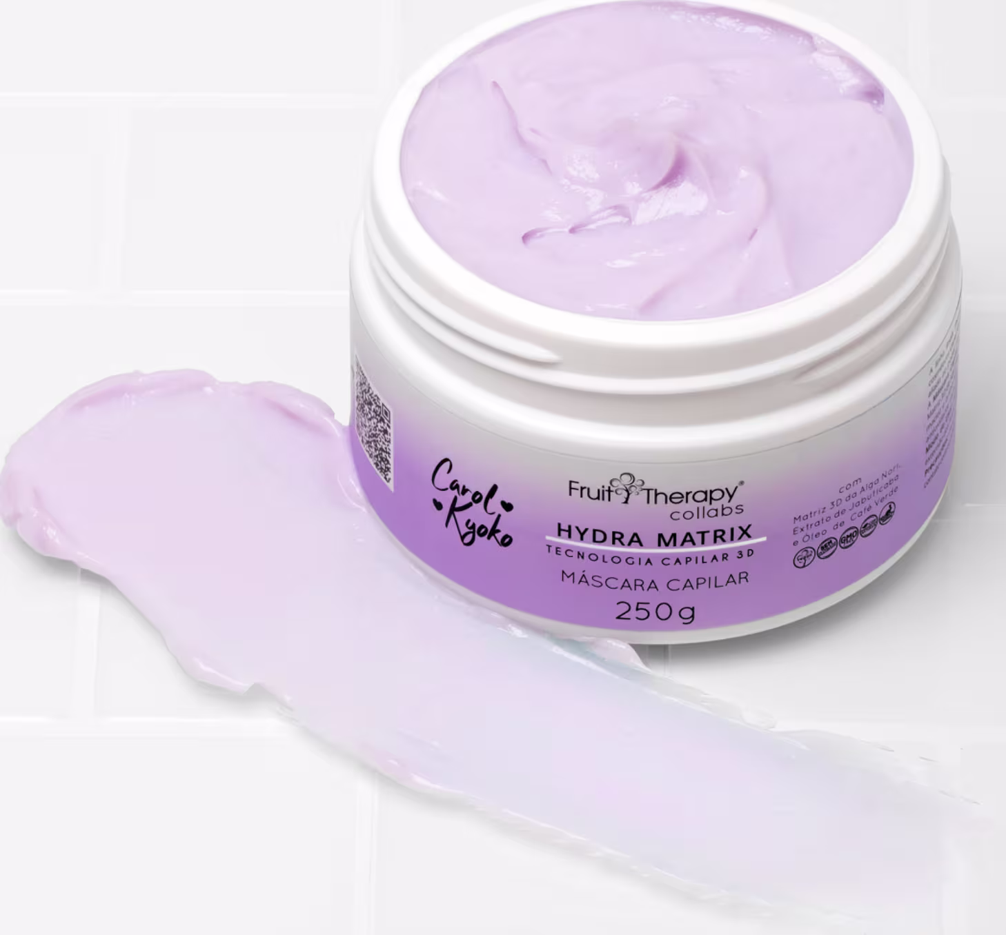 A imagem mostra um produto de tratamento capilar hidratante. O pote de 250g é branco com detalhes na cor lilás claro está aberto e posicionado sobre uma superfície branca, com um pouco do seu conteúdo espalhado nela.