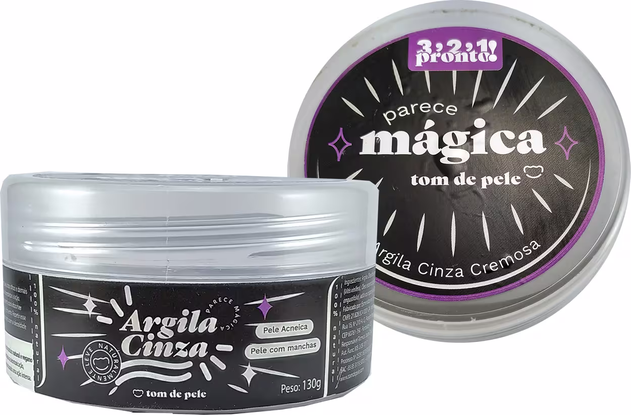 O produto apresentado é um creme de argila cinza da marca Tom de Pele, chamado "Argila Cinza Mágica". O rótulo exibe o nome do produto, "Argila Cinza Mágica", bem como informações sobre o tipo de pele a que se destina, "Pele Acneica" e "Pele com Manchas"