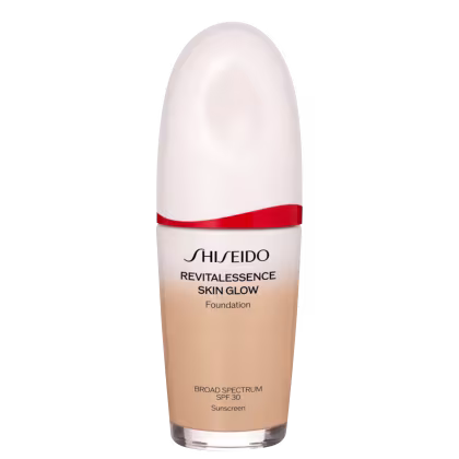A imagem mostra um frasco de base líquida da marca Shiseido. O produto se chama "RevitaLessence Skin Glow Foundation". Trata-se de uma base com proteção solar SPF 30 e propriedades que prometem dar um brilho saudável à pele (skin glow).