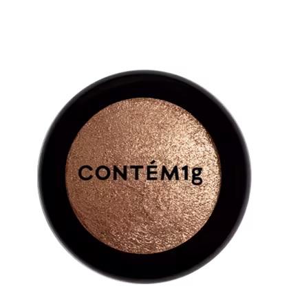 A imagem mostra uma embalagem de pó iluminador cor dourada e no centro, a logo da marca em preto.