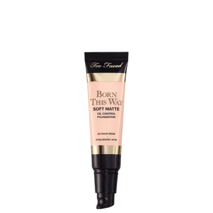 A imagem mostra uma embalagem pequena, sem a tampa, tipo bisnaga, de base líquida, cor muito clara. A embalagem tem detalhes bege e preto, com letra pretas e dourada.