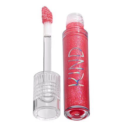 A imagem mostra a tampa da embalagem do gloss, com o aplicador virado pra cima, semelhante a uma tampa de batom, transparente e cilíndrica. Ao lado, o frasco do gloss, com o produto de cor coral e com a palavra KIND escrito na embalagem.