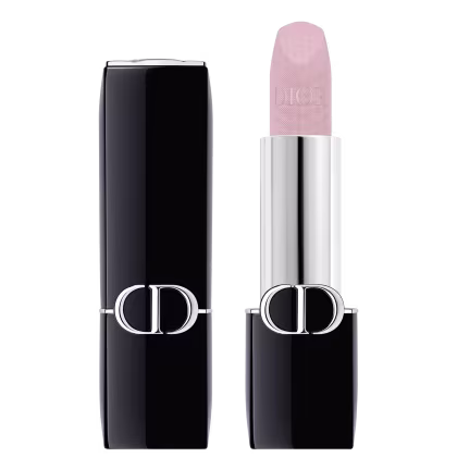 A imagem mostra uma embalagem de balm labial, tipo bala, rosa, com a tampa ao lado. A embalagem é preta e prata com o logo da marca em prata.
