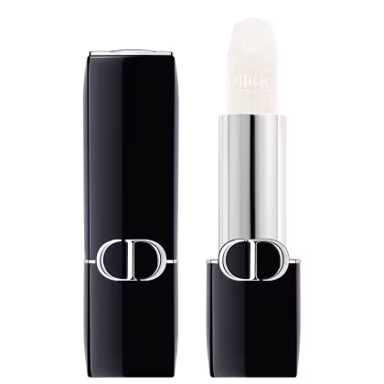 A imagem mostra uma embalagem de balm labial, tipo bala, branco, com a tampa ao lado. A embalagem é preta e prata com o logo da marca em prata.
