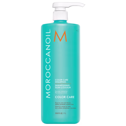 A imagem mostra o Shampoo Color Care 1L da marca Moroccanoil. Embalagem plástica na cor azul turquesa, com letras brancas e pretas e logotipo da marca em laranja. O frasco tem uma bomba dosadora branca na parte superior.