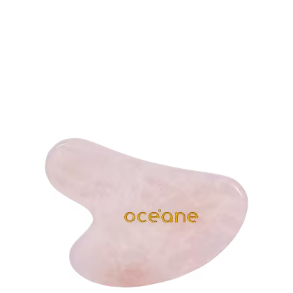 Gua sha em quartzo rosa com a logo da marca em letras douradas.