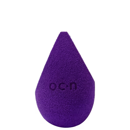 Esponja de maquiagem roxo escuro com textura aveludada. Formato de gota com a palavra "Océane" impressa em relevo na superfície.