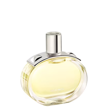 A imagem mostra o perfume Barénia de Hermès. Seu frasco é de vidro arredondado e transparente, permitindo ver o líquido amarelado em seu interior. Sua tampa é cilíndrica e prateada e possui uma aplicação com pinos em forma de pirâmide com facetas curvas.