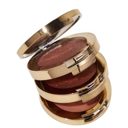 A embalagens é composta por várias camadas circulares que se encaixam, com superfícies espelhadas e detalhes metálicos brilhantes. As tampas superiores são achatadas e apresentam um acabamento liso e polido.