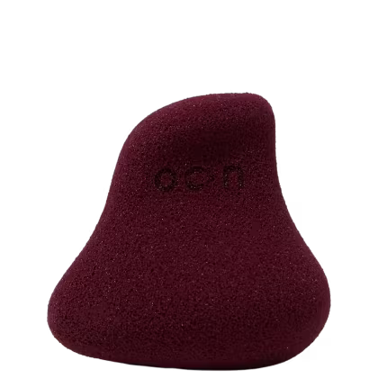 Esponja de maquiagem facial em formato de gota, com textura porosa e cor vinho escura. O produto possui uma aparência aveludada e macia. Não há rótulos ou texto visível.