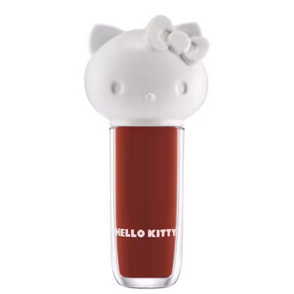 Maquiagem em formato cilíndrico com a cabeça da personagem Hello Kitty como tampa. A parte superior é rosa com detalhes em relevo que representam os olhos, orelhas e laço da Hello Kitty. É possível ver a cor do produto pelo corpo transparente.
