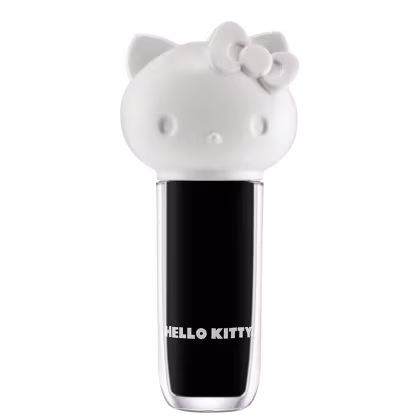 Maquiagem em formato cilíndrico com a cabeça da personagem Hello Kitty como tampa. A parte superior é branca com detalhes em relevo que representam os olhos, orelhas e laço da Hello Kitty. É possível ver a cor do produto pelo corpo transparente.