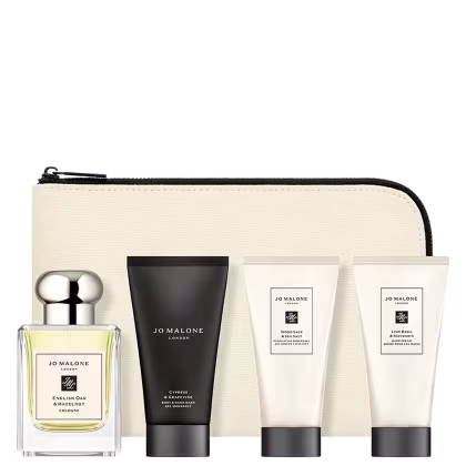 A imagem mostra uma variedade de produtos de cuidados pessoais da marca Jo Malone e ao fundo um lindo nécessaire em tons claros.