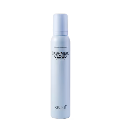 A imagem mostra a Mousse Keune Cashmere Cloud em frasco branco fosco. Embalagem cilíndrica com tampa protetora na cor azul claro. Nome do produto "Cashmere Cloud" e a marca "Keune" em letras pretas. Descrição adicional "Dry volumizing mousse"
