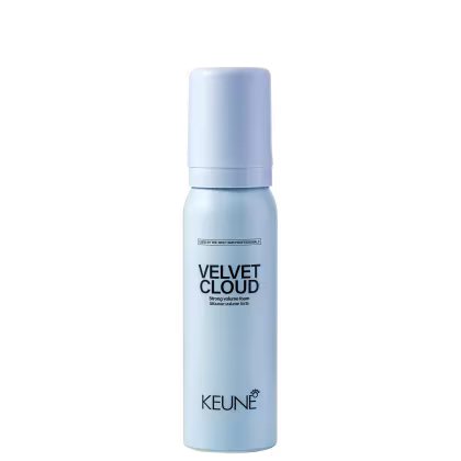 A imagem mostra a Mousse Volumadora Velvet Cloud da marca Keune. É apresentado em um frasco cilíndrico branco azulado opaco. Exibe o nome do produto "Velvet Cloud" em letras pretas maiúsculas, seguido da descrição "Mousse volume foam" em letras menores.