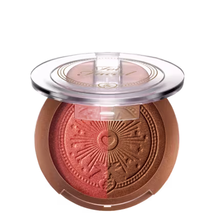 Pó bronzeador compacto em embalagem redonda de plástico transparente, com detalhes dourados e um desenho de sol estampado no centro. O produto possui uma tonalidade dourada brilhante.