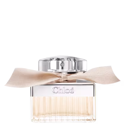 Frasco de perfume Chloé com tampa de metal e laço bege. Embalagem de vidro transparente com rótulo em relevo com o nome da marca. Produto de beleza com design elegante e sofisticado.