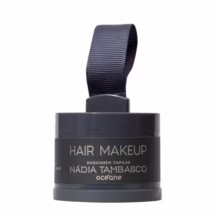 Embalagem preta com rótulo "Hair Makeup" da marca Océane, contendo maquiagem capilar da designer Nádia Tambasco. Recipiente com tampa e alça de tecido preto, apresentando informações sobre o produto em destaque.