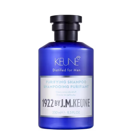 Shampoo em um frasco é azul translúcido, permitindo ver o líquido de cor azul vibrante dentro. A embalagem tem uma tampa preta e apresenta o nome da marca Keune, o nome da linha Distilled for Men e a descrição "Purifying Shampoo" em letras brancas.