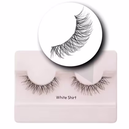 A imagem mostra os cílios postiços em um estojo plástico claro. O estojo tem uma cor nude claro e exibe um par de cílios postiços pretos.