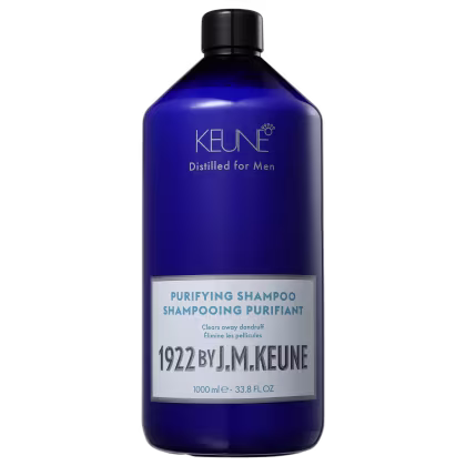 Shampoo em um frasco é azul translúcido, permitindo ver o líquido de cor azul vibrante dentro. A embalagem tem uma tampa preta e apresenta o nome da marca Keune, o nome da linha Distilled for Men e a descrição "Purifying Shampoo" em letras brancas.