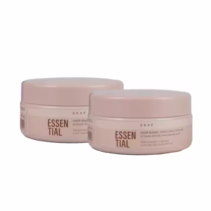 Dois potes de máscara capilar da marca Braé, com embalagens redondas de cor rosa clara. Os rótulos exibem o nome "Essential" em destaque, indicando que se trata de um produto da linha Essential da marca.
