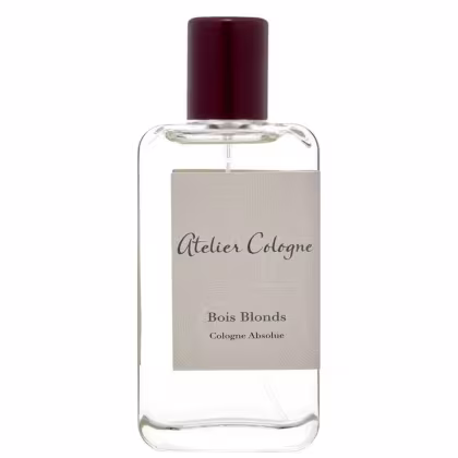 Perfume em frasco de vidro transparente retangular com tampa de plástico marrom escuro. Rótulo bege com o texto "Atelier Cologne" e "Bois Blonds Cologne Absolue" impresso em letras escuras.