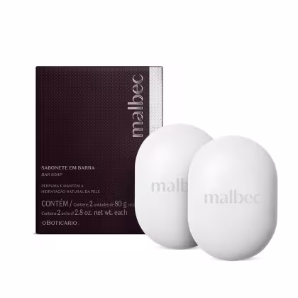 A embalagem é de cor marrom escura com o nome da marca em destaque. O sabonete é branco e vem em duas unidades de 80g cada. A embalagem indica que o produto perfuma e mantém a hidratação natural da pele.
