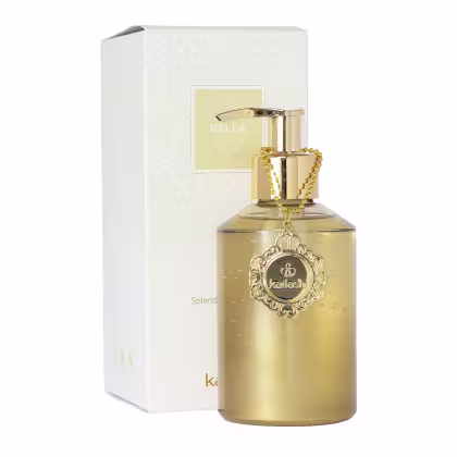 Frasco de sabonete líquido dourado da marca Kailash Bella, com rótulo e embalagem decorativa em branco e dourado. O frasco possui um pingente dourado com detalhes ornamentais.